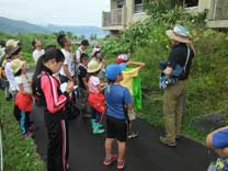 有珠山金比羅火口の散策路途中にある噴火遺構の旧町民住宅で説明を聞く参加者